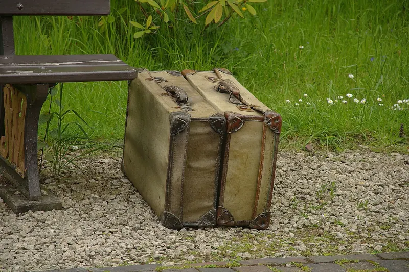 Two vintage suitcases resting by a wooden bench