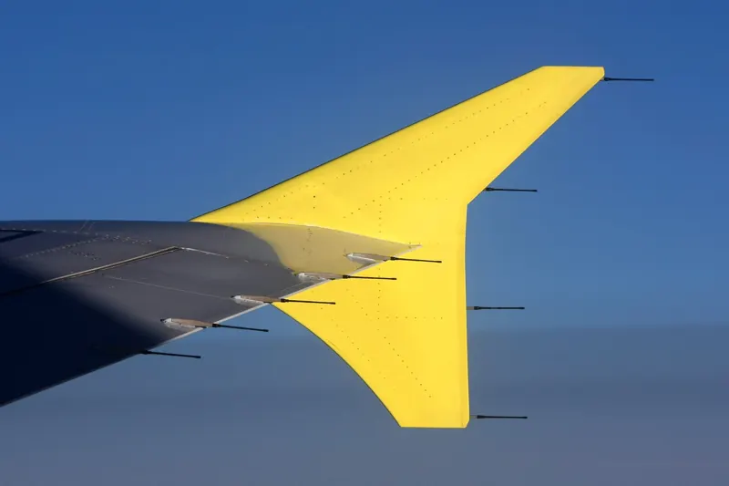 A yellow airplane wingtip against a deep blue sky